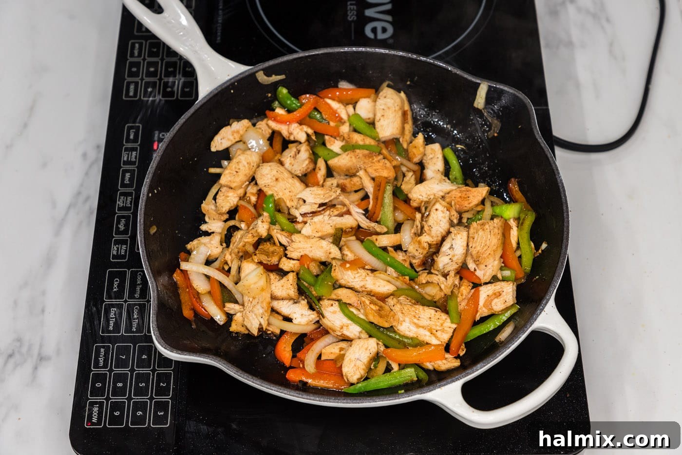 sliced chicken added to skillet with bell peppers and onion