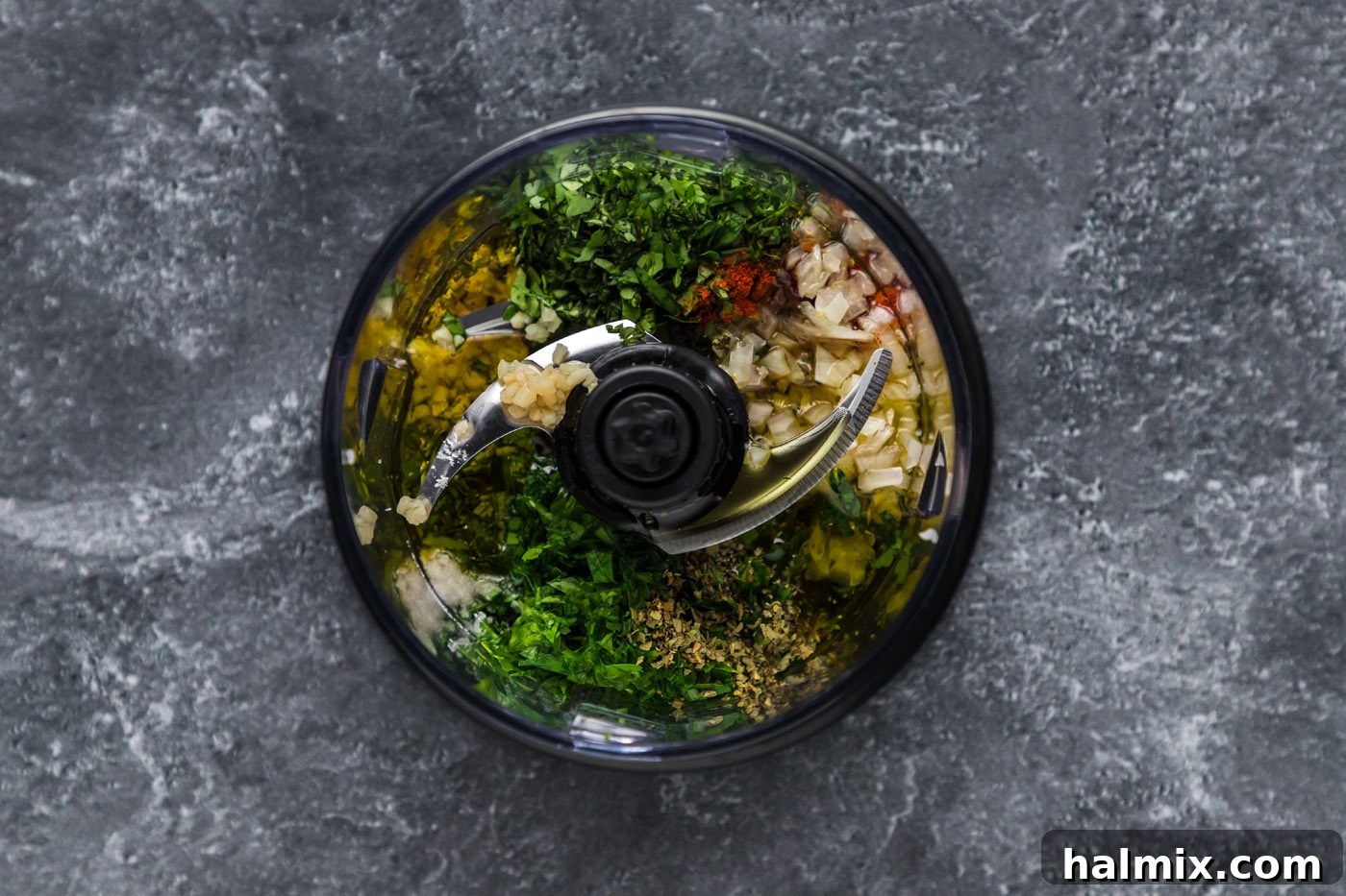 Pulsing Chimichurri Ingredients Chimichurri ingredients being pulsed in a mini food processor.