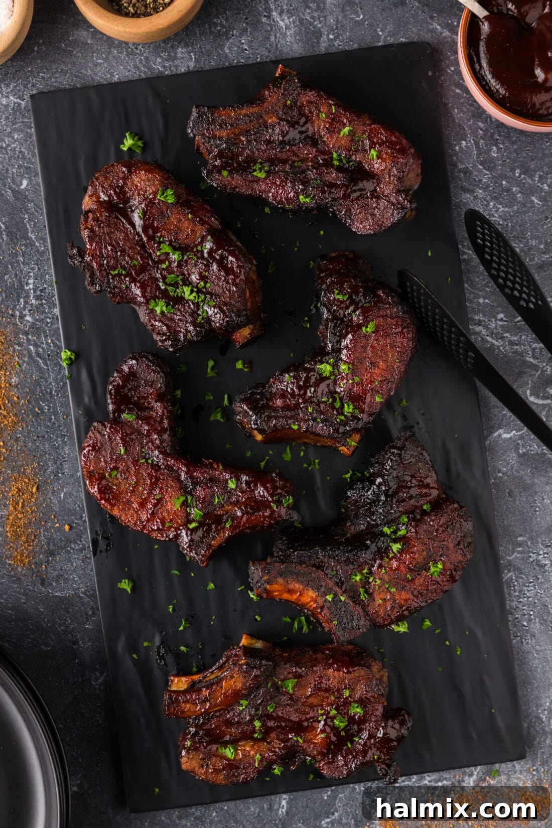 Two perfectly cooked Country Style Ribs served on a rustic black platter, showcasing their juicy tenderness.