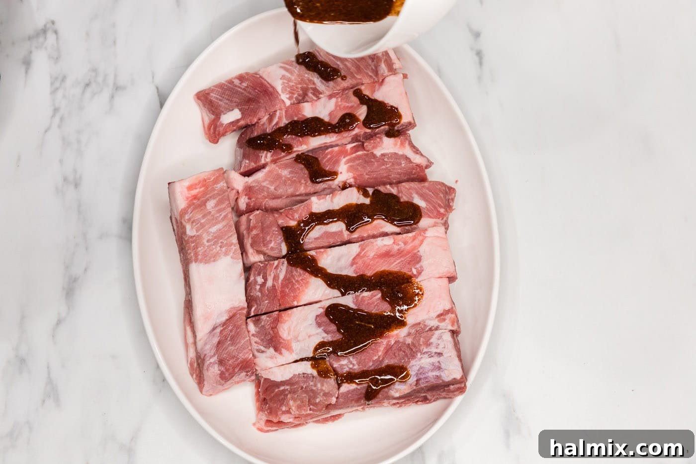 Expertly topping country style ribs with the wet rub, ensuring an even coating on all sides.