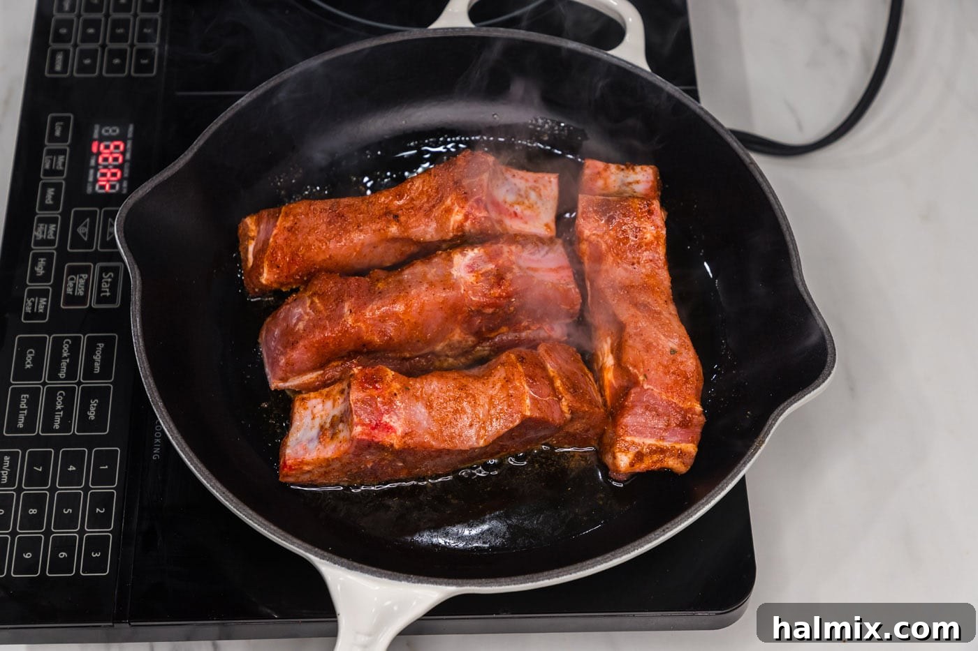 Searing country style ribs in a hot skillet, creating a perfect crust.