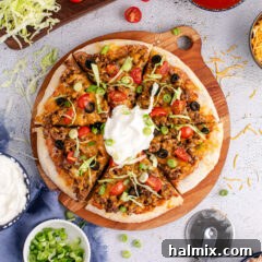 Taco Pizza cut into slices topped with sour cream