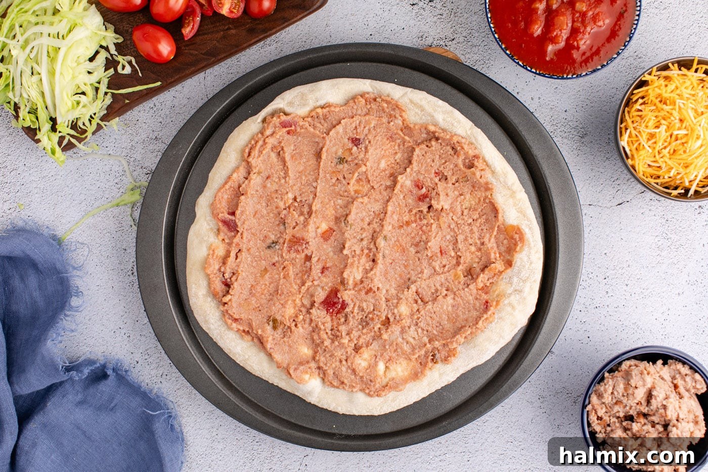 Layer of refried beans and salsa spread over a pizza crust