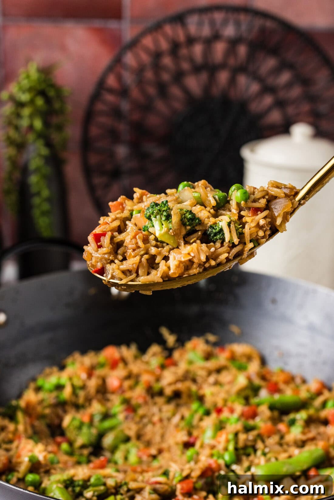 Spoonful of Vegetable Fried Rice held above a wok of Vegetable Fried Rice