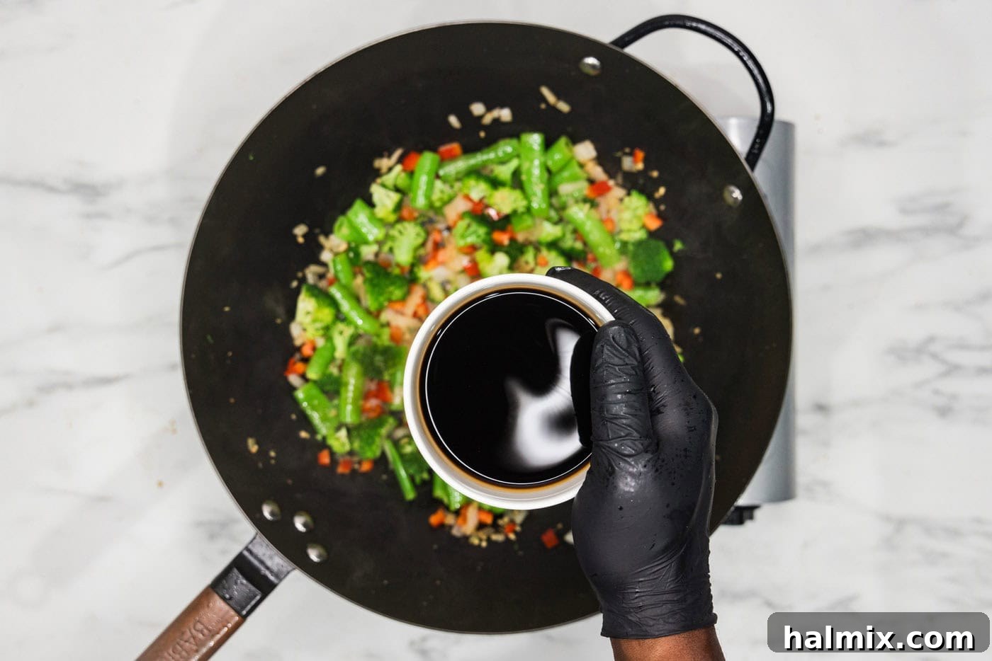 Soy sauce in a bowl over wok with vegetables