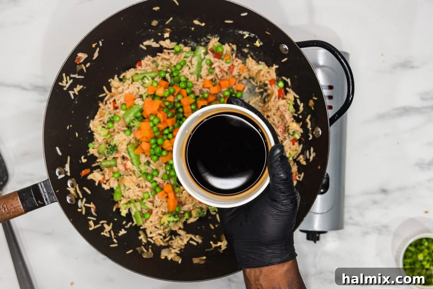 adding soy sauce to wok with vegetable fried rice