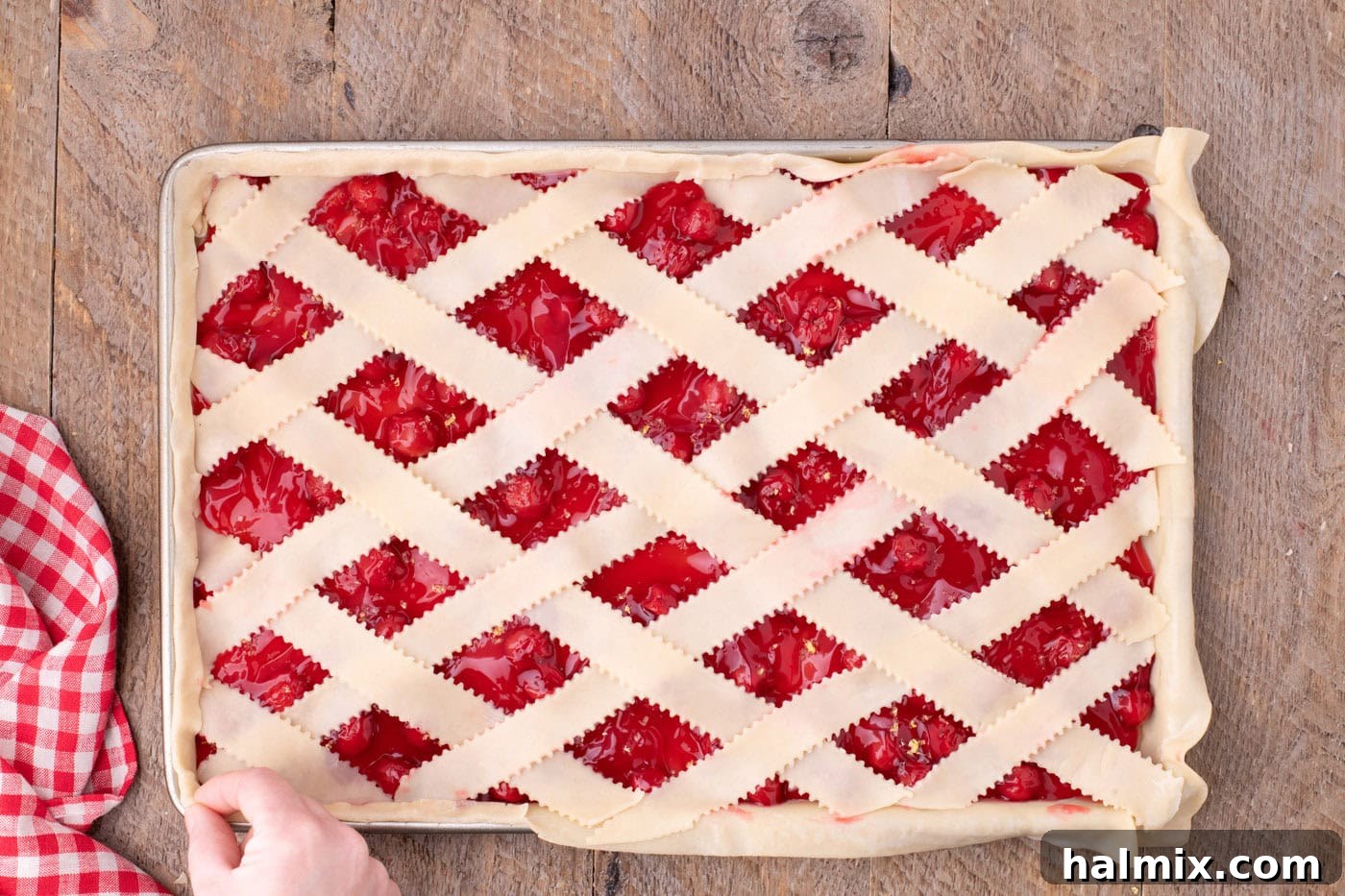 pinching seams of pie crust together to seal edges of cherry slab pie