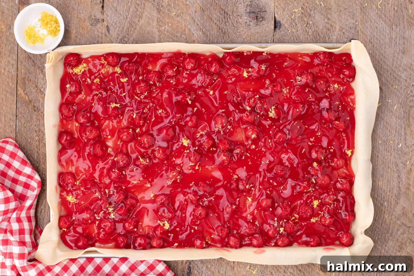 cherry pie filling on top of pie crust in a jelly roll pan