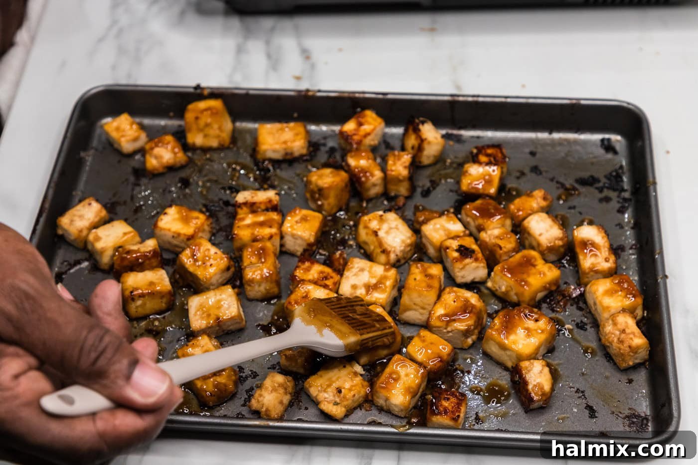 Sticky Honey Garlic Tofu 12 Brushing crispy tofu cubes with the luscious honey garlic sauce, creating a sticky, flavorful glaze.