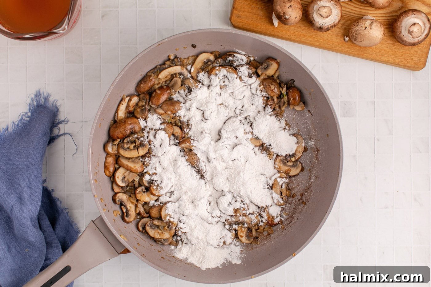 Flour added to the skillet with sauteed onion and mushrooms, forming a roux