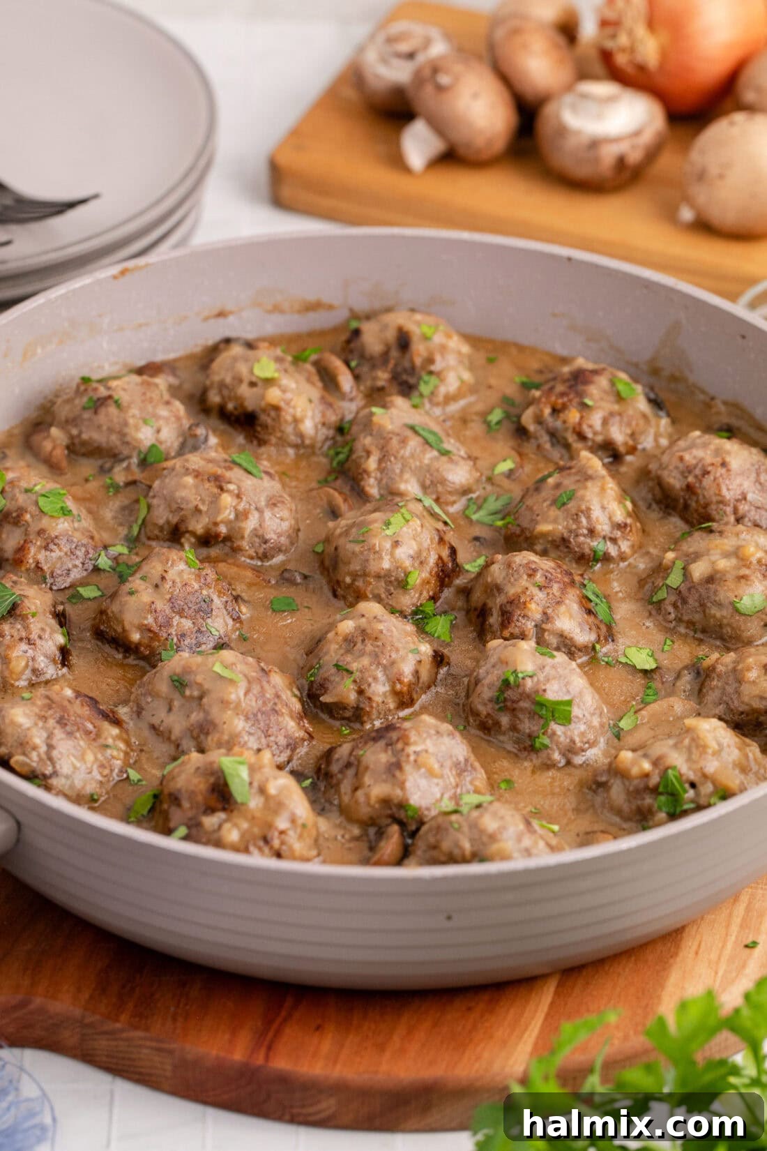 A close-up shot of a skillet filled with Salisbury Steak Meatballs smothered in rich mushroom gravy, garnished with fresh herbs.