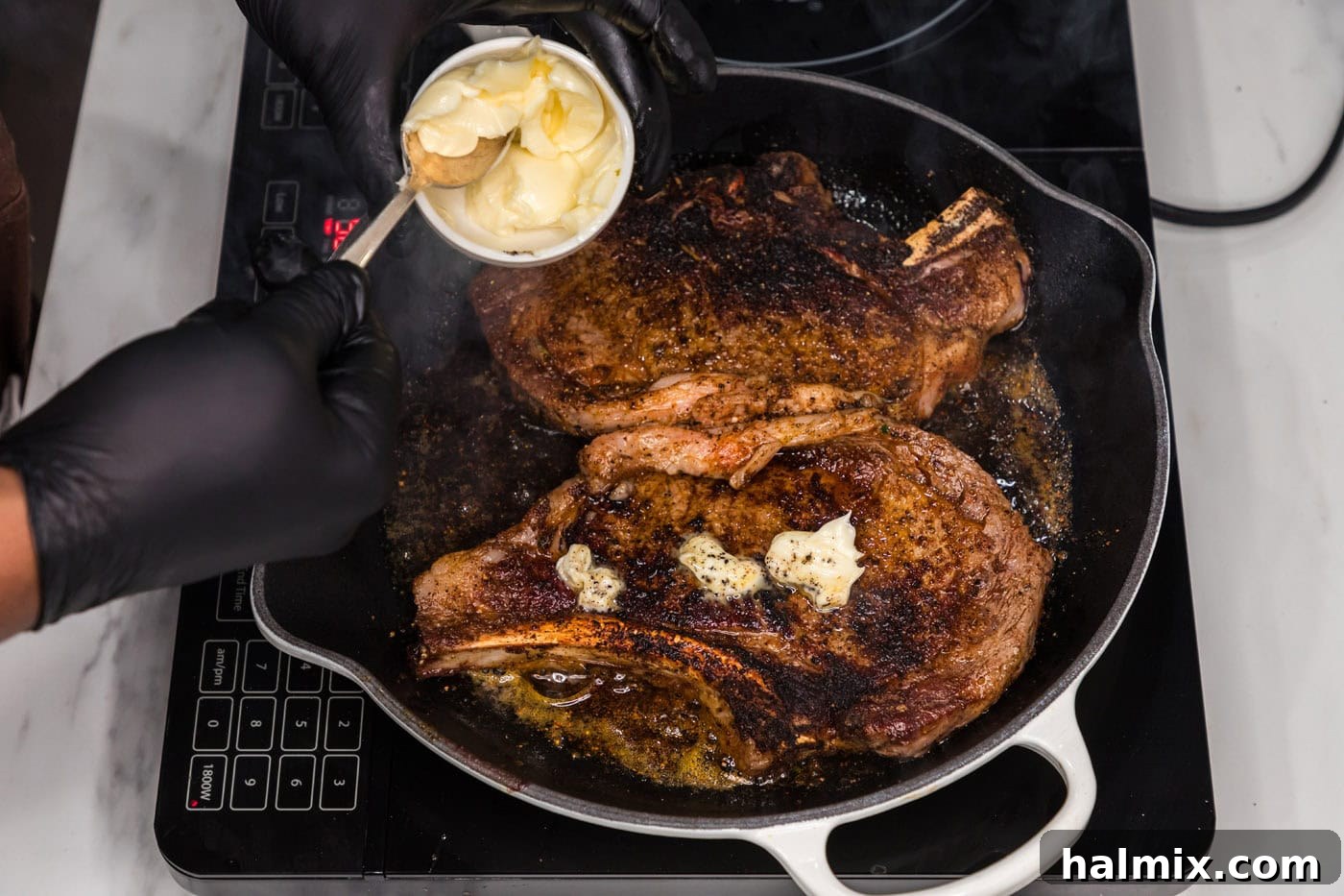 adding butter on top of ribeye steaks in a skillet