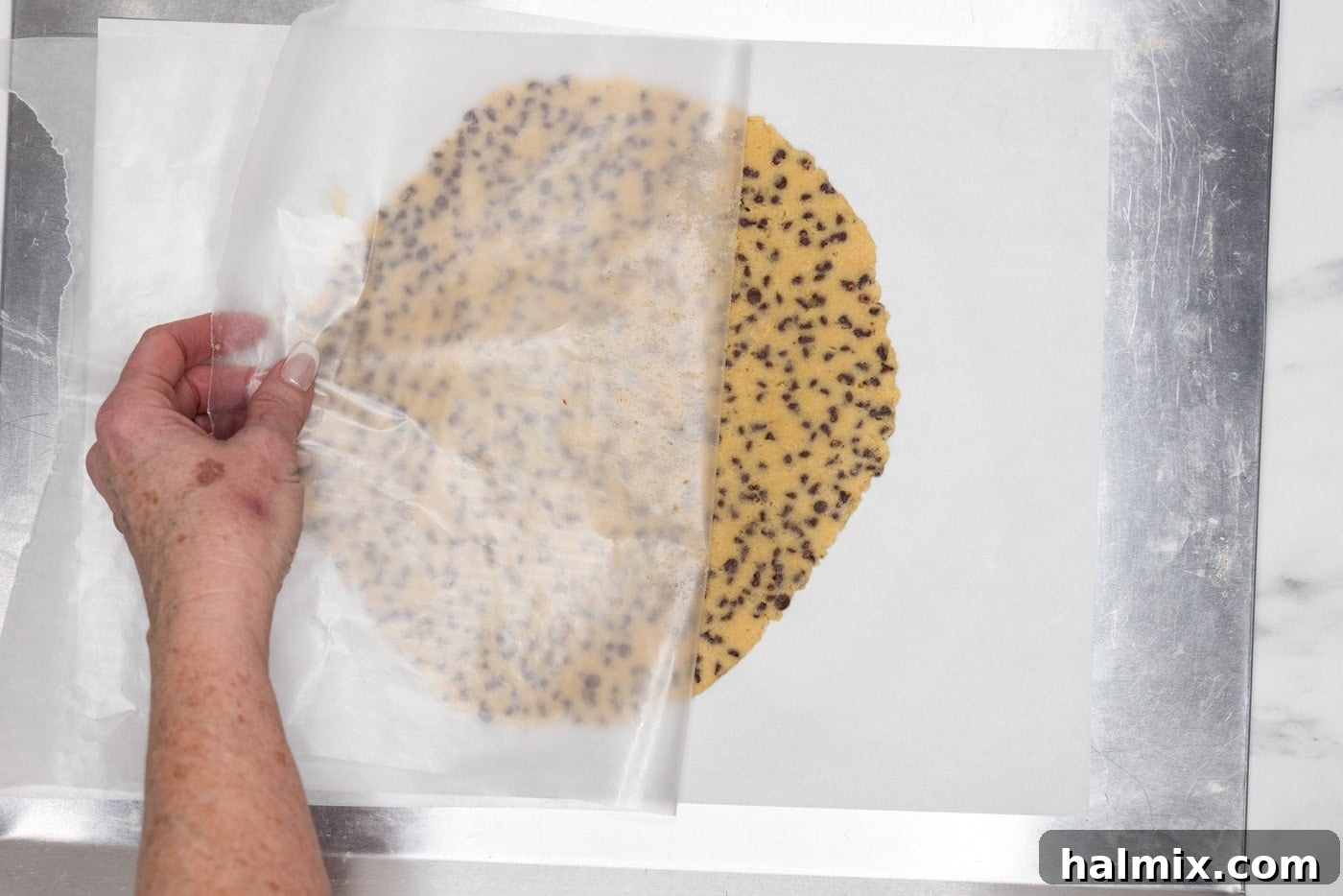peeling parchment paper off rolled out cookie dough
