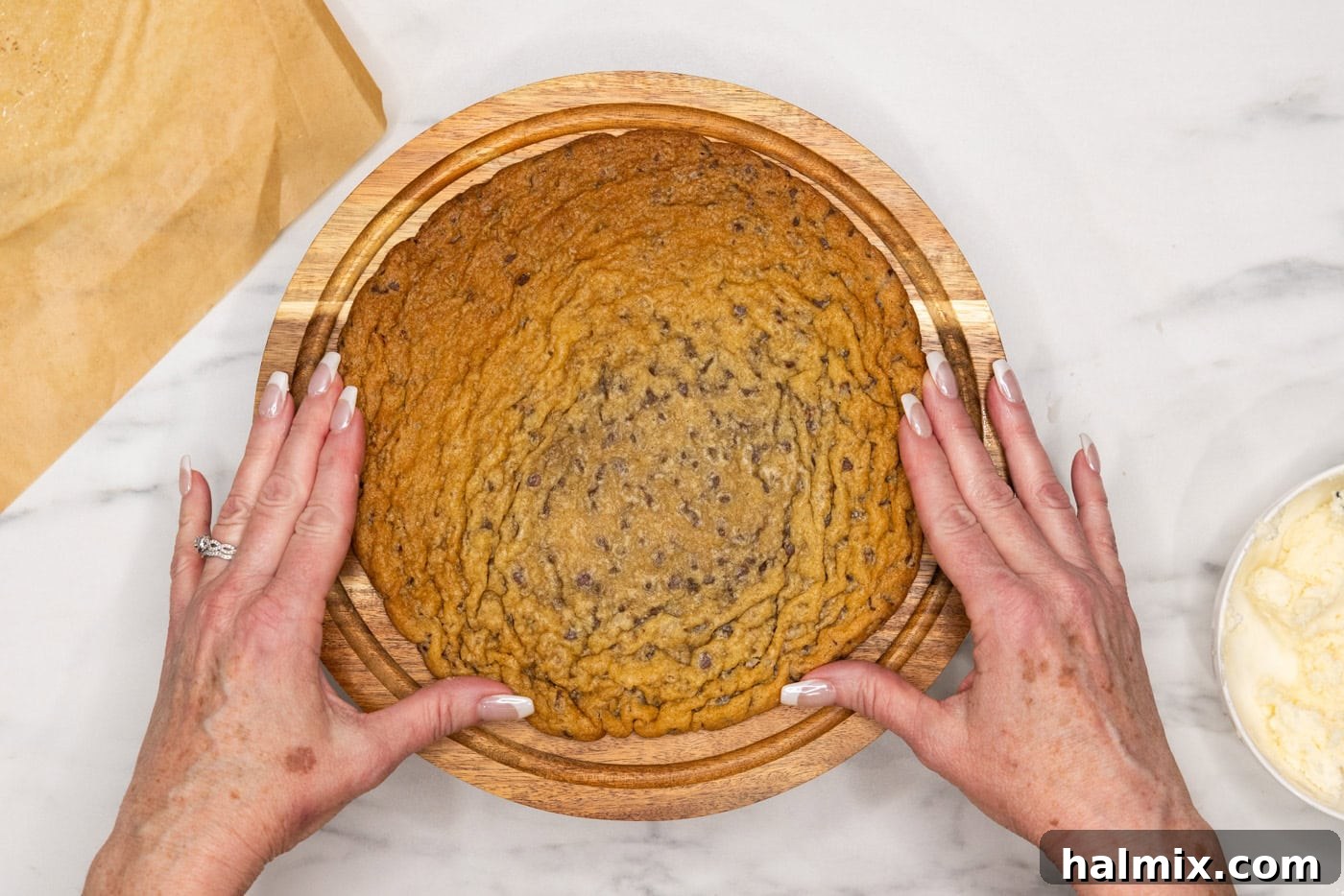 placing jumbo chocolate chip cookie onto cake stand