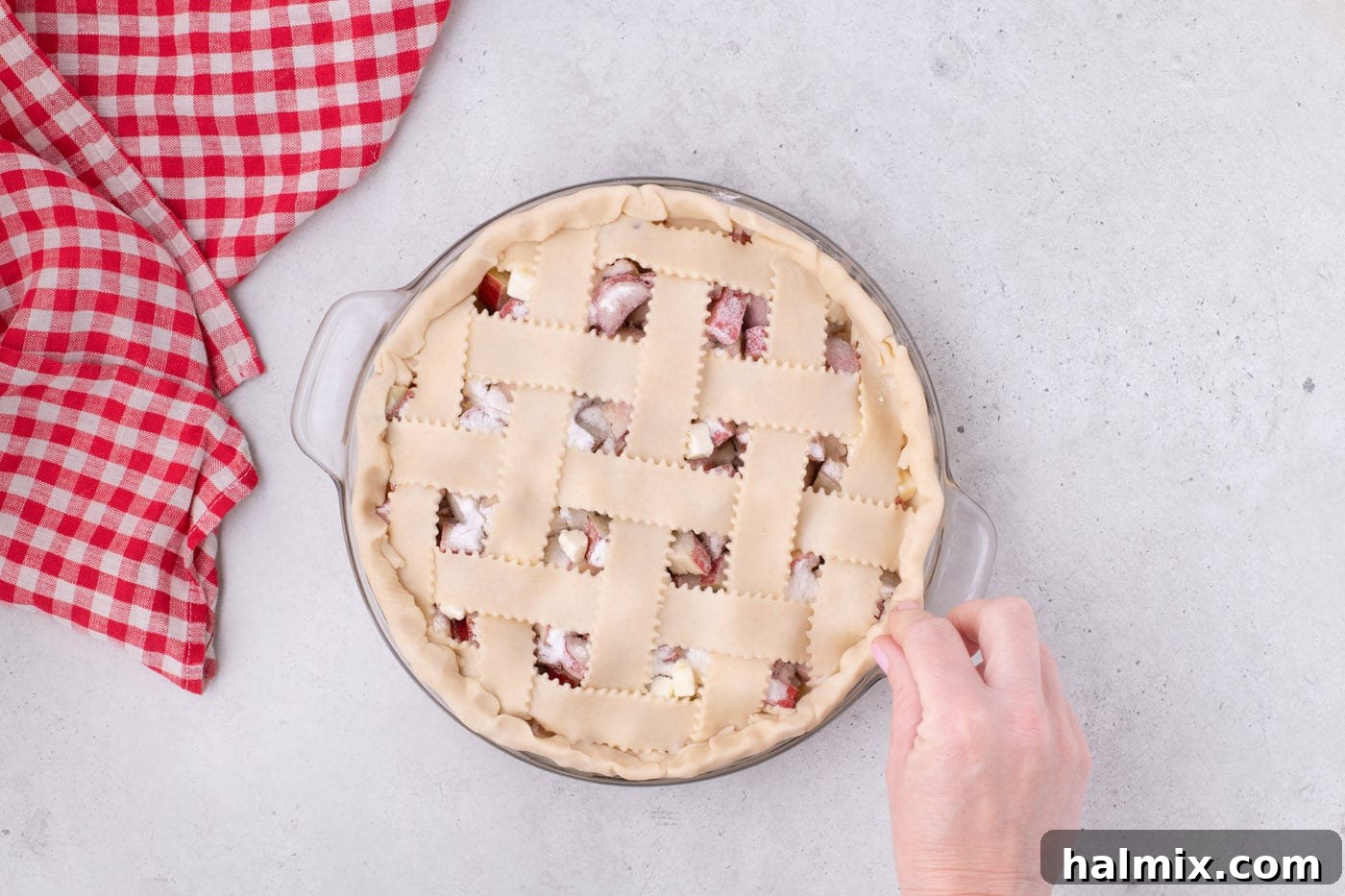 Tangy Rhubarb Delight 17 The edges of the pie crust and lattice strips being pinched together to create a sealed and decorative crust.