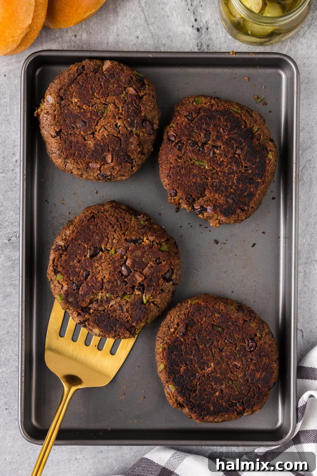 Four Black Bean Burger patties on a baking sheet with a spatula 
