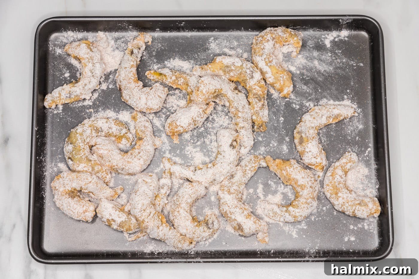 Thunder Shrimp 11 Flour-dredged shrimp arranged on a baking sheet, ready for frying.