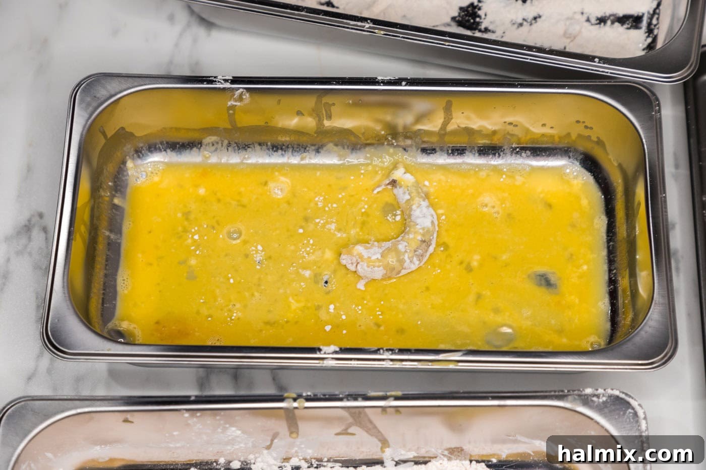 Thunder Shrimp 9 Floured shrimp being dipped into the egg wash.