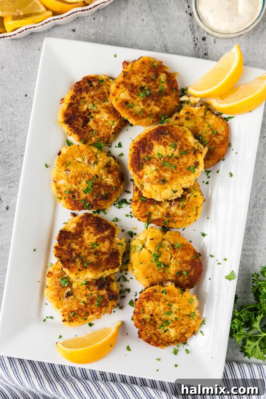 Golden Cod Fritters 3 Cod Fish Cakes on a platter with fresh lemon wedges