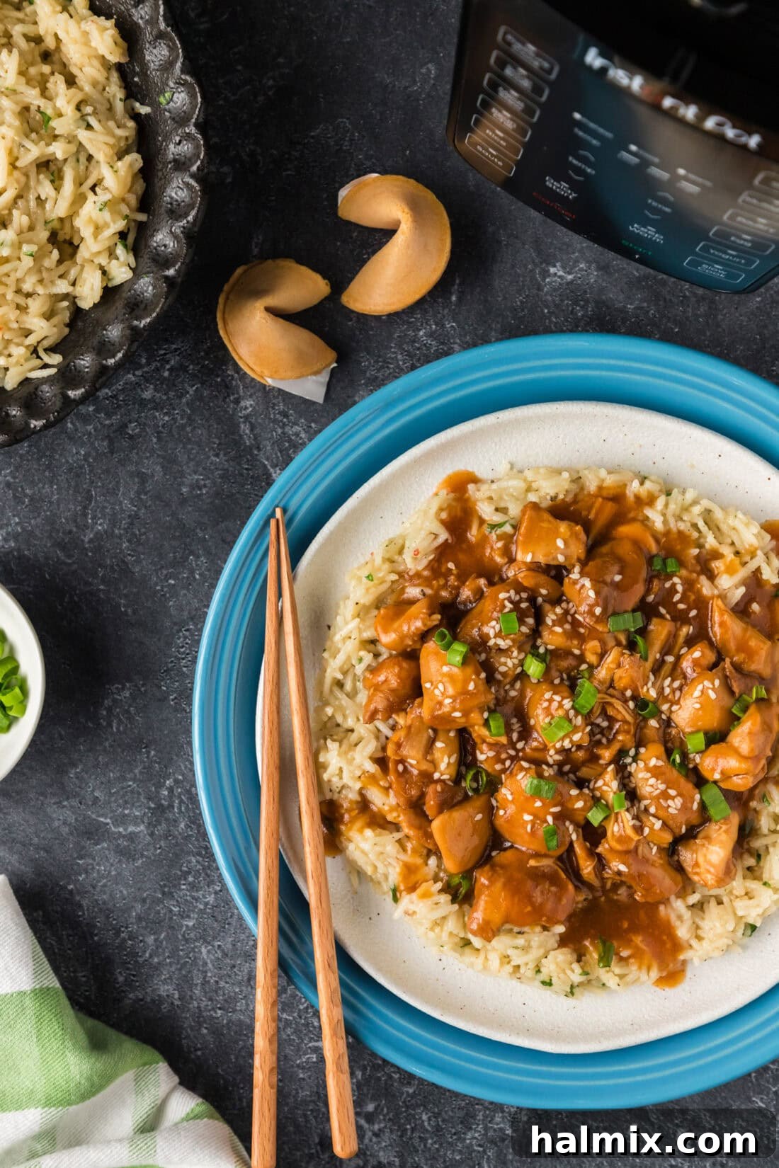 Sweet and Sticky Instant Pot Bourbon Chicken 2 Half a plate of Instant Pot Bourbon Chicken served over fluffy white rice, with fortune cookies subtly blurred in the background, hinting at a delightful meal experience.