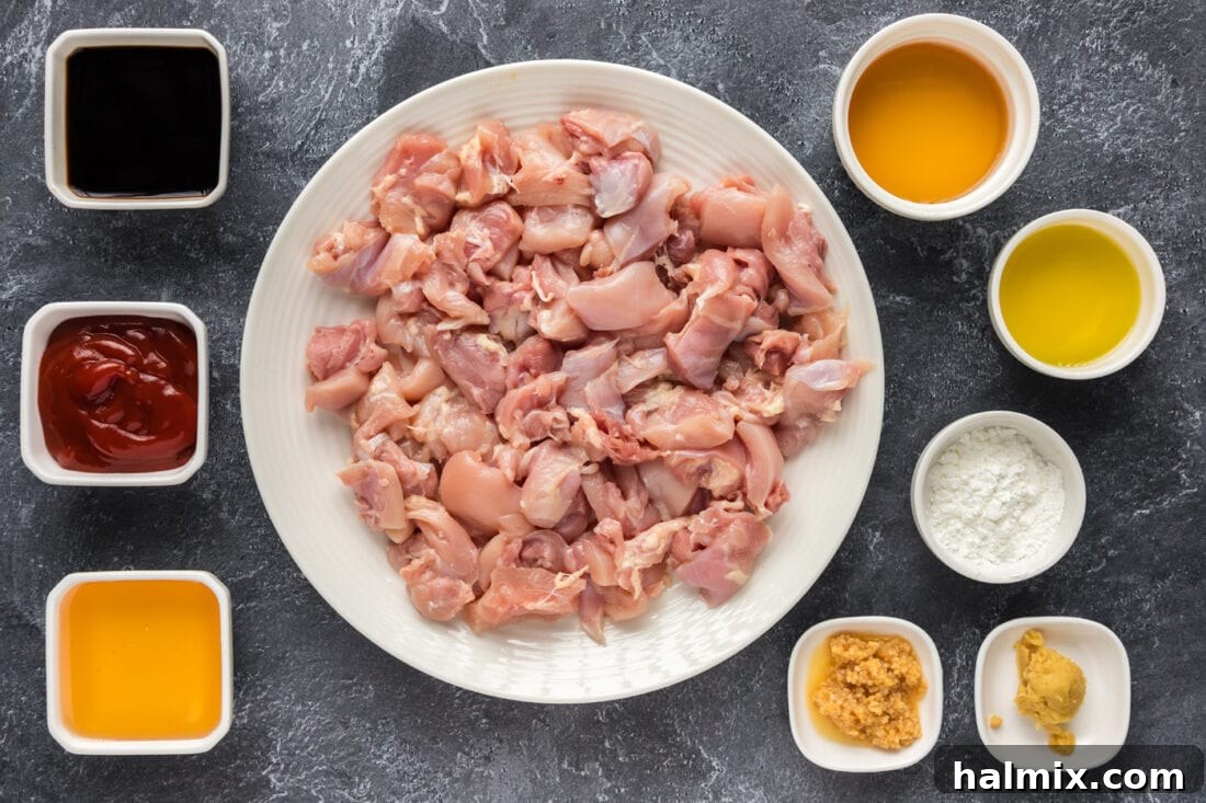 Sweet and Sticky Instant Pot Bourbon Chicken 4 A collection of fresh ingredients laid out on a clean surface, including chicken thighs, bottles of soy sauce and ketchup, a jar of honey, minced garlic and ginger, and a small bottle of bourbon, ready for making Instant Pot Bourbon Chicken.