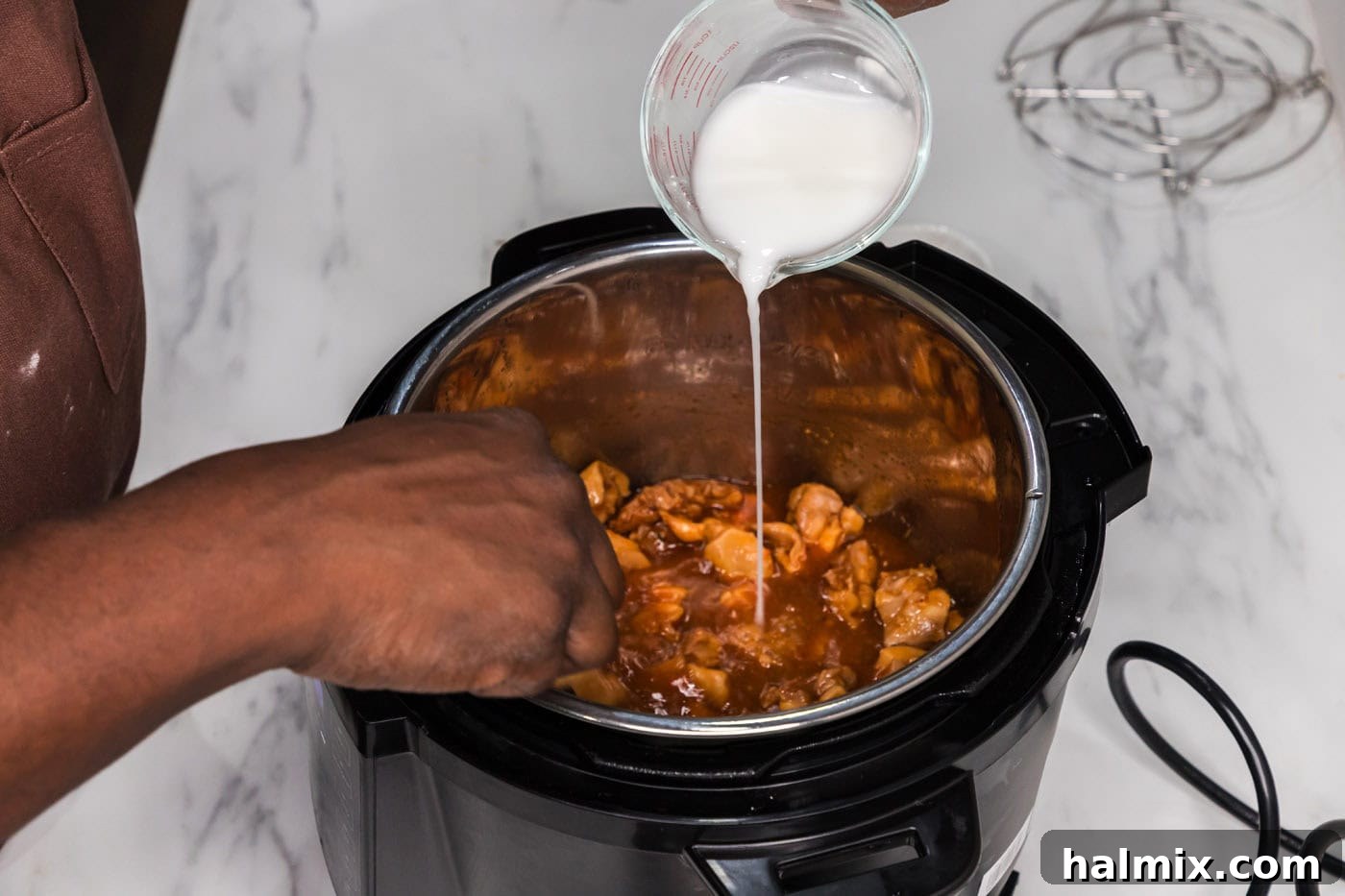 Sweet and Sticky Instant Pot Bourbon Chicken 7 A cornstarch slurry being gently poured into the Instant Pot, where the bourbon chicken sauce is simmering, illustrating the thickening process for a perfect glaze.