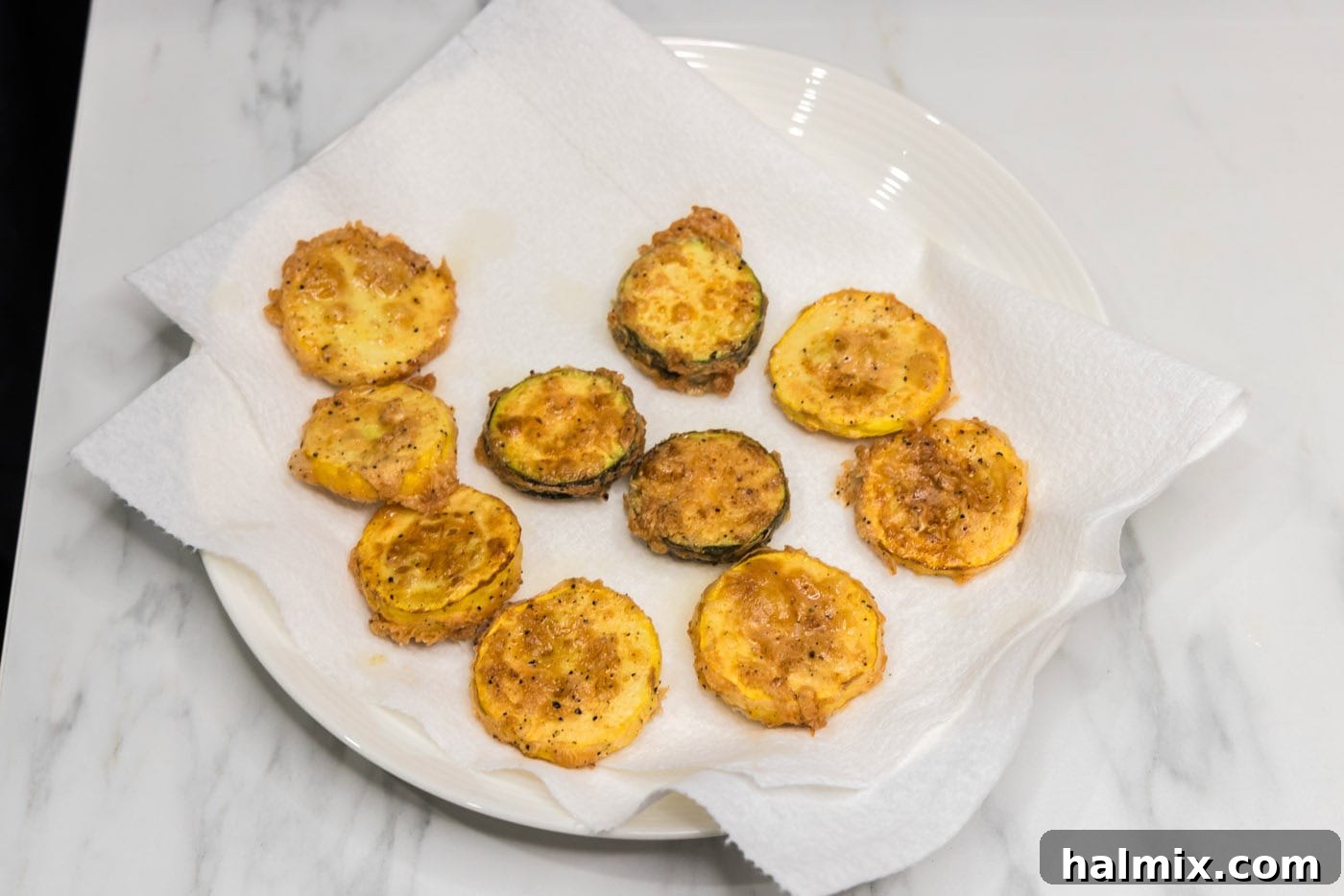Golden Fried Squash 11 Freshly fried squash pieces draining on a bed of paper towels to remove excess oil.
