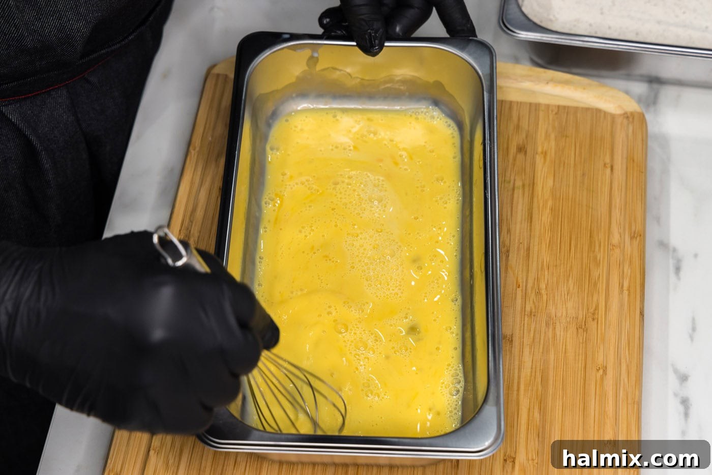Golden Fried Squash 7 A whisk being used to combine eggs and buttermilk in a breading tray.