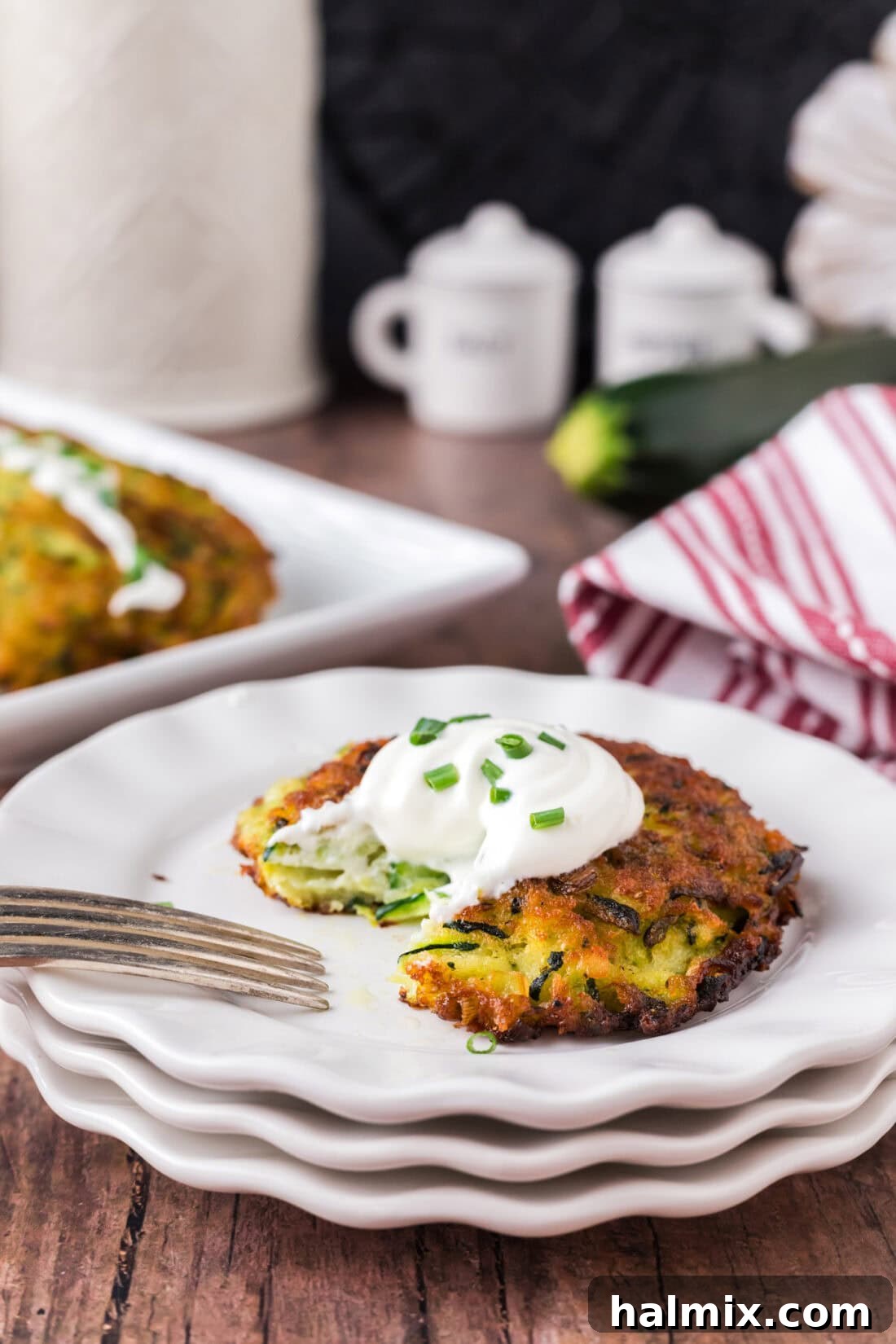 Golden Zucchini Delights 12 A single Zucchini Fritter on a white plate with a bite removed, showing the tender interior