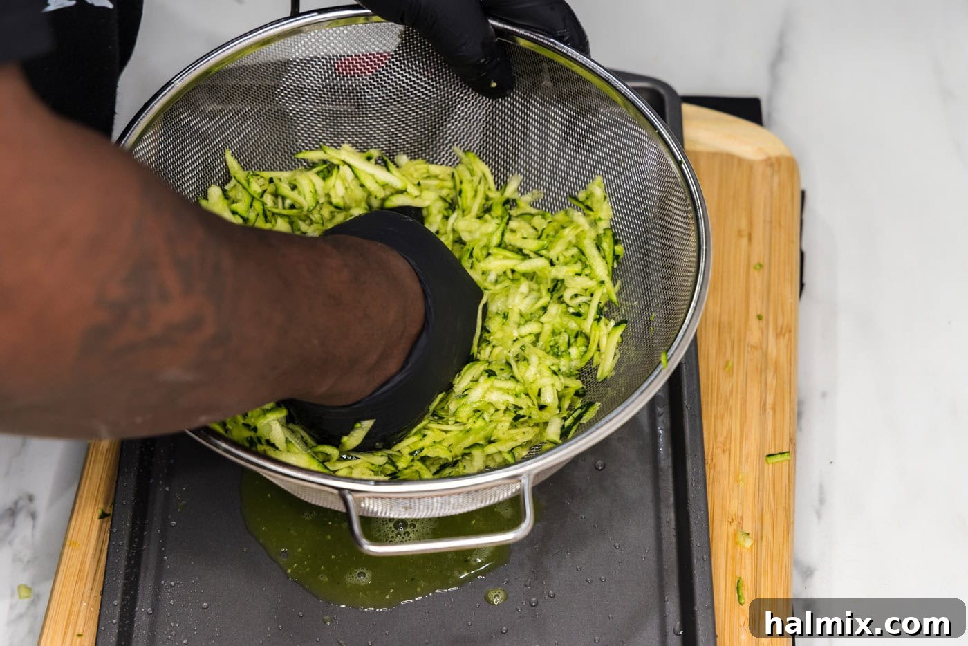 Golden Zucchini Delights 6 Hands squeezing moisture out of shredded zucchini in a colander