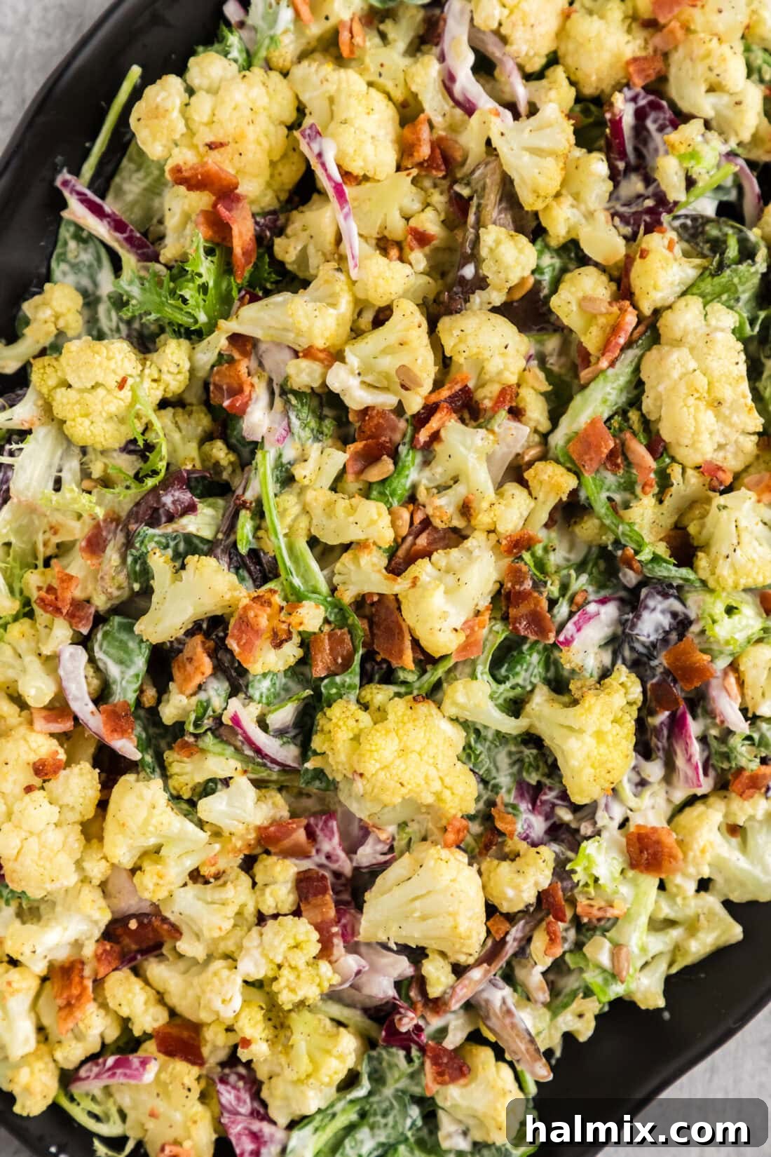 Close up photo of Creamy Cauliflower Salad, showing the roasted florets, bacon, and dressing.
