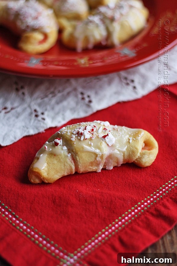 Snowy Peppermint Crescents 3 A close up photo of a white chocolate candy cane crescent on a red napkin.