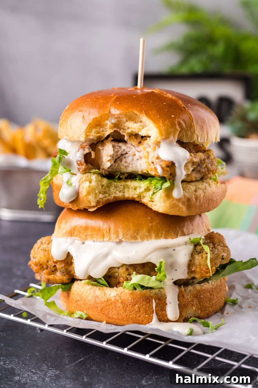 Two Crispy Chicken Burgers stacked on top of each other with a bite taken out of the top one