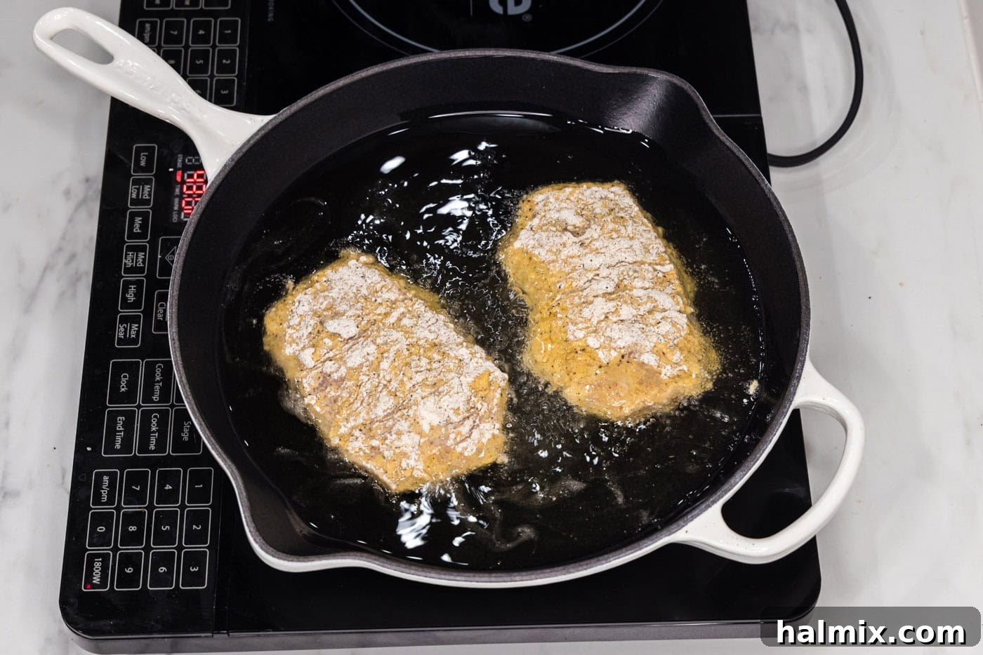 frying chicken burgers over hot oil in a skillet