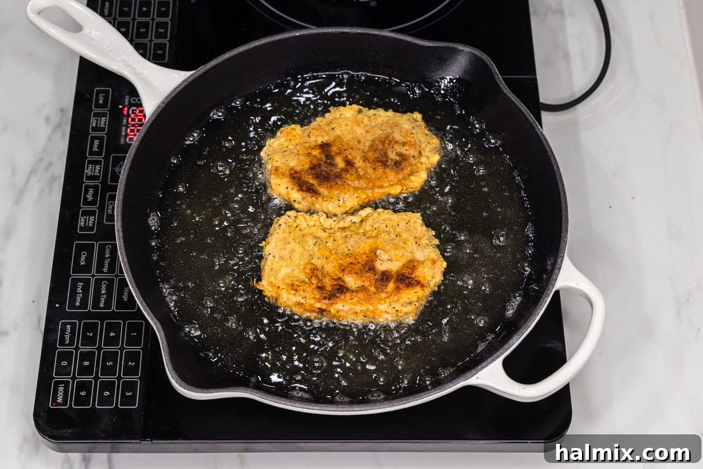 fried chicken burgers in a skillet with oil