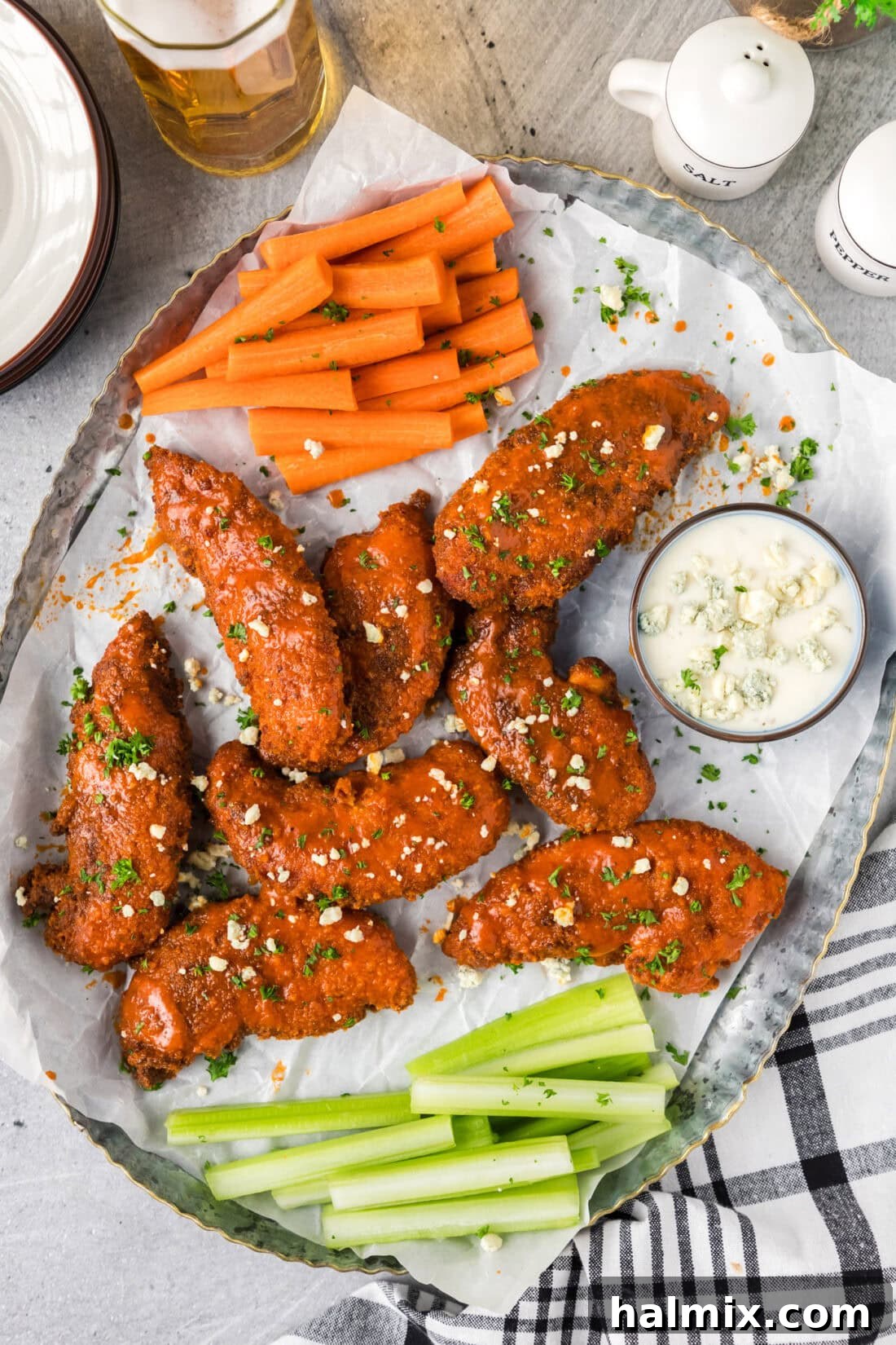 Buffalo Chicken Tenders on a parchment lined platter with carrots, celery and ranch on the side