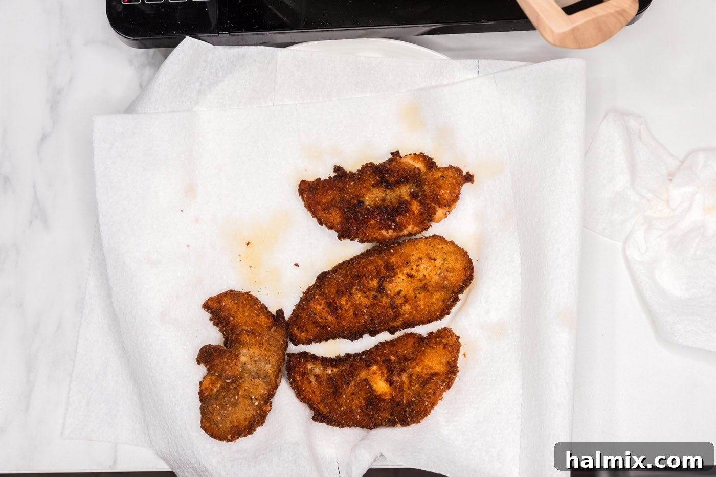 crispy fried chicken tenders draining on paper towels