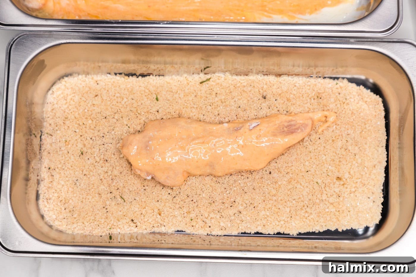 dredged buffalo chicken added to pan of breadcrumb mixture