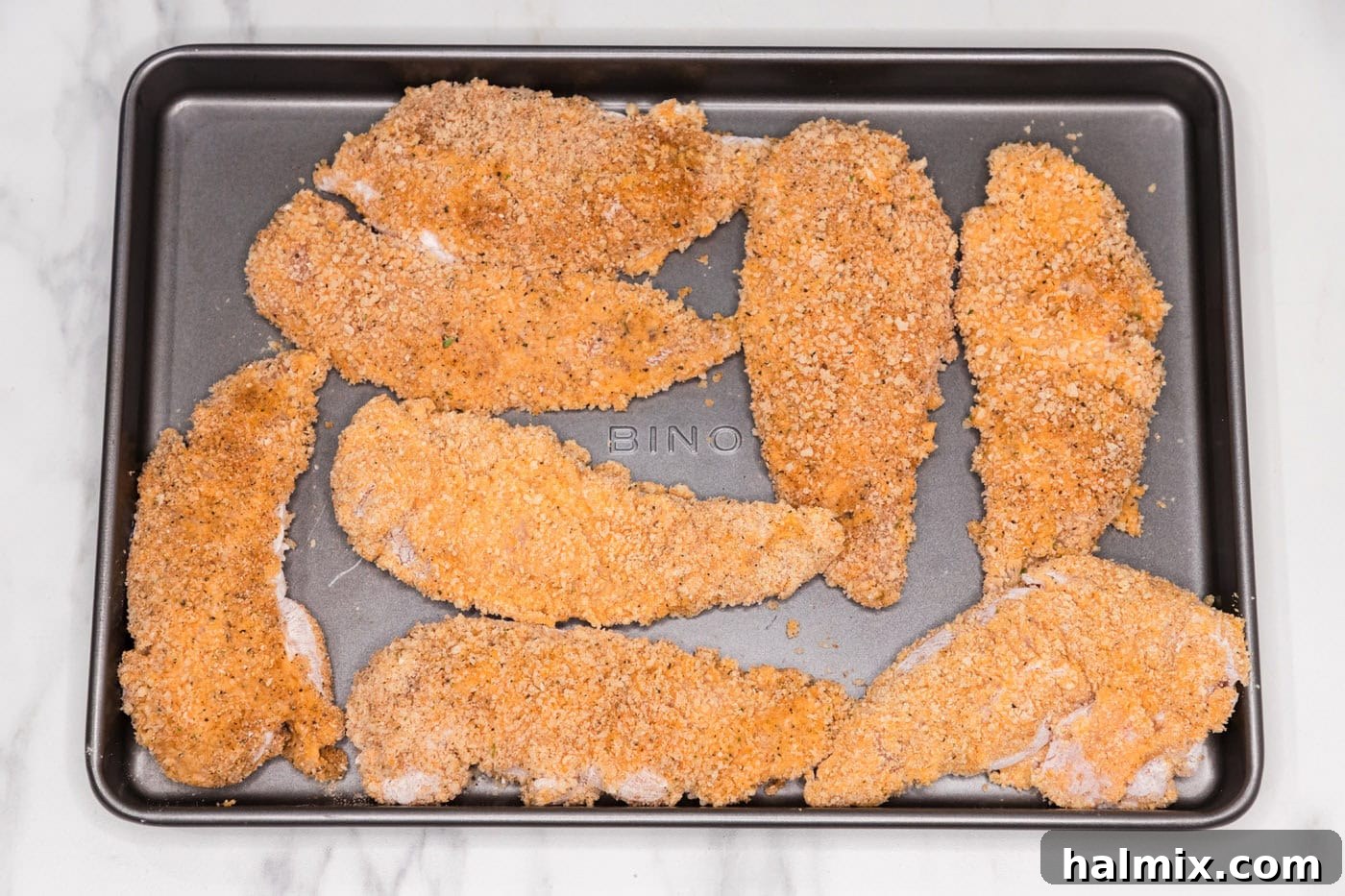 panko breadcrumb coated chicken tenders on a baking sheet