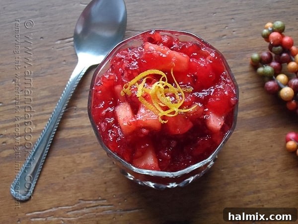 A close-up photo of cranberry orange relish in a beautiful glass bowl with a serving spoon next to it, highlighting its vibrant color and texture.