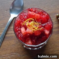 A close up photo of cranberry relish in a glass bowl with a spoon laying next to it.