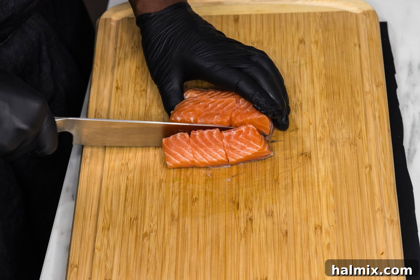 Golden Air Fryer Salmon Bites 5 knife slicing salmon into cubes on a cutting board