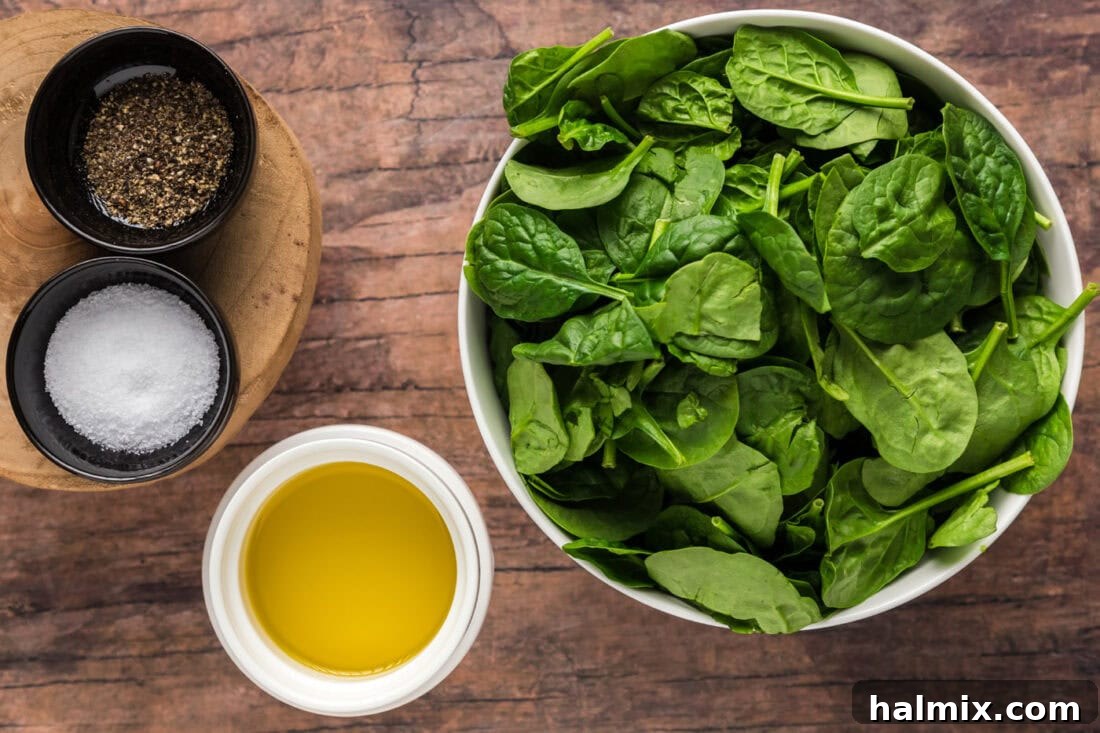 A collection of ingredients laid out on a cutting board, including fresh spinach, olive oil, and seasonings, prepared for making air fryer spinach.