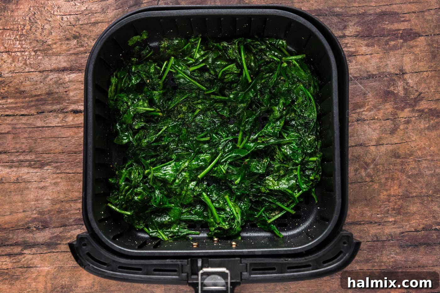 Cooked air fryer spinach in the air fryer basket, showing its tender texture.