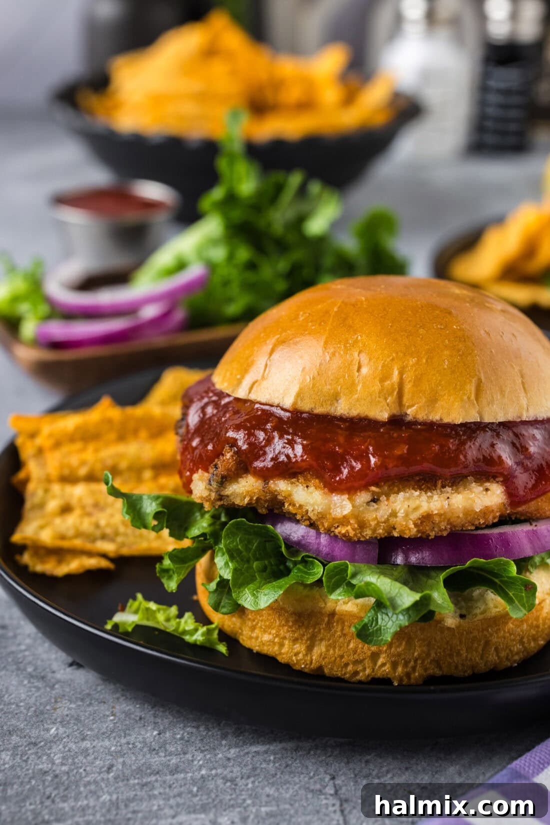 Close up photo of a Shrimp Burger on a plate with chips on the side, showing the crispy texture.
