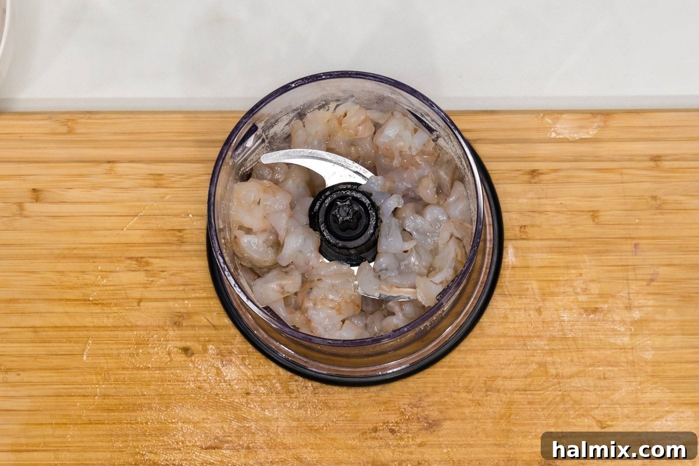 The first batch of raw shrimp, butter, Dijon, and seasonings in a mini food chopper, ready to be blended.
