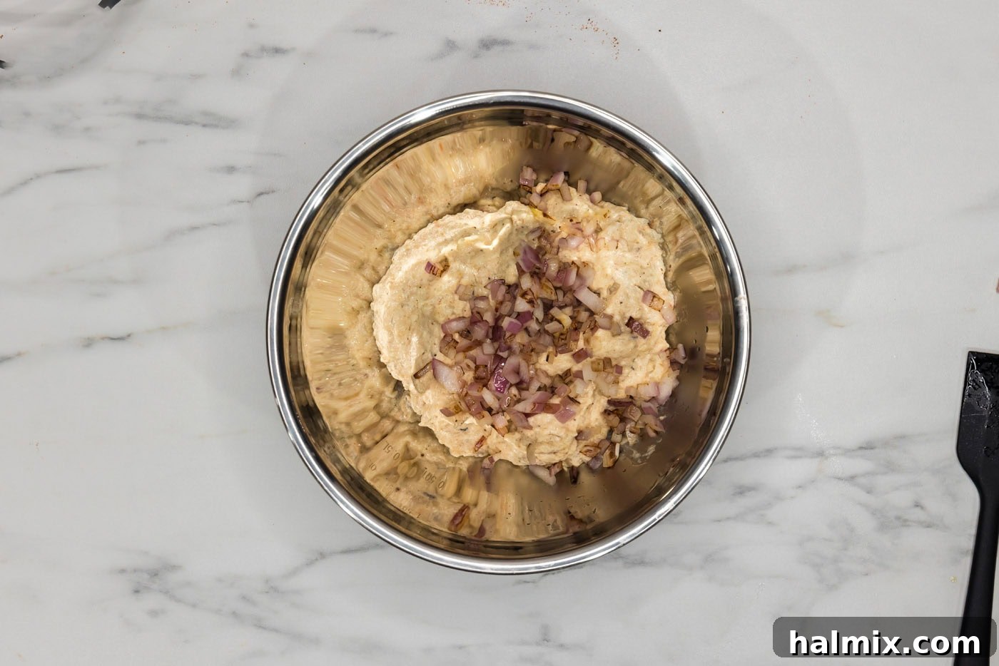 Sautéed red onions being added to the shrimp burger patty ingredients in a bowl.