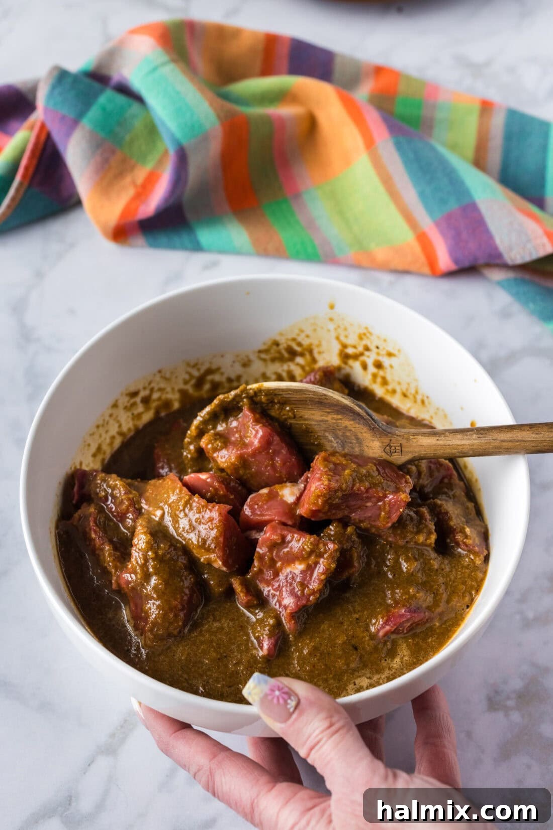 Sweet & Smoky Bourbon Marinade 3 A spoon stirring pieces of steak coated in the luscious Bourbon Marinade within a mixing bowl, ready for marinating.