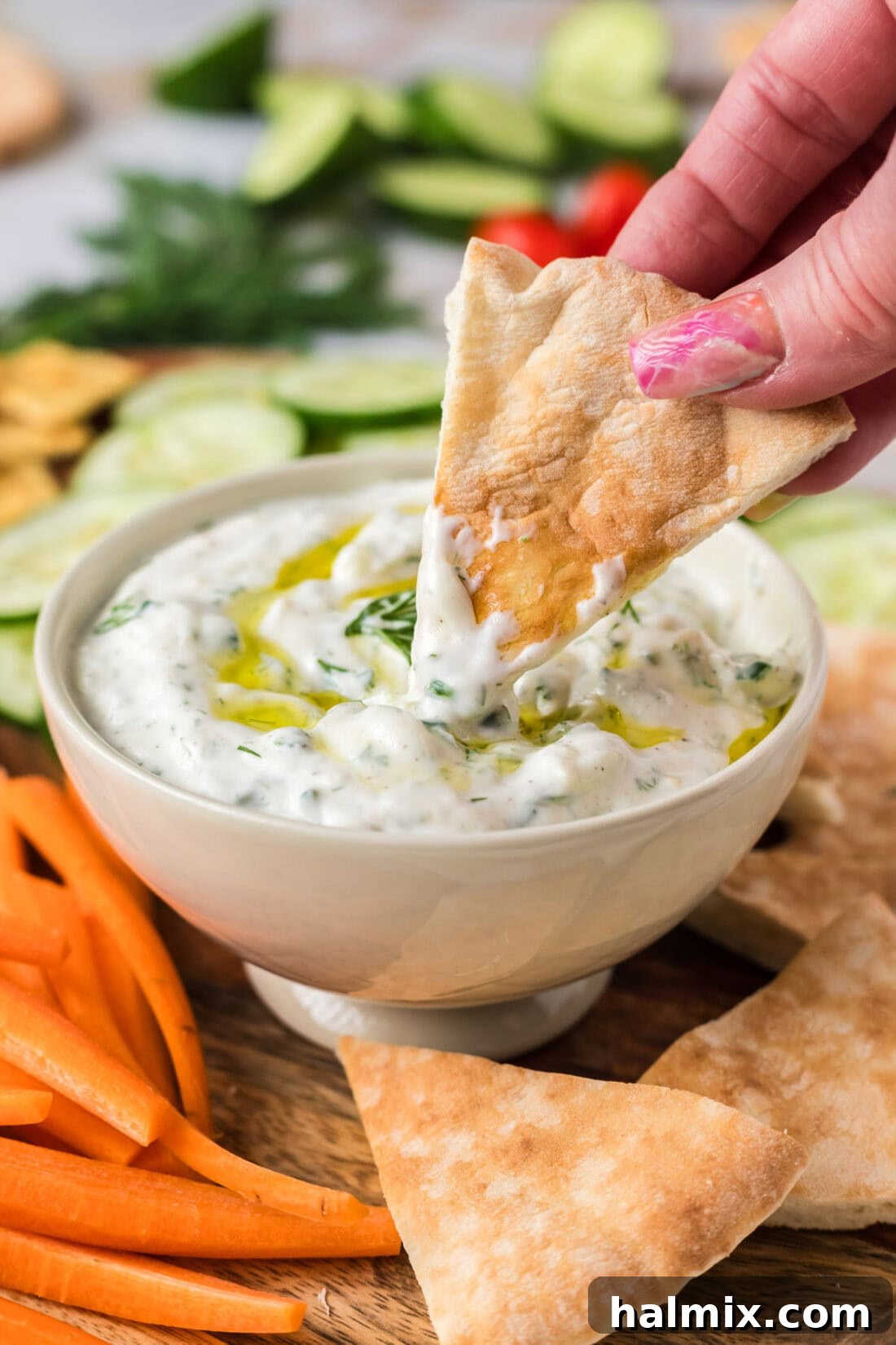 Golden pita bread being dipped into a bowl of creamy, homemade Tzatziki Sauce, showcasing its perfect dipping consistency and inviting texture, ready to be enjoyed as a snack or appetizer.
