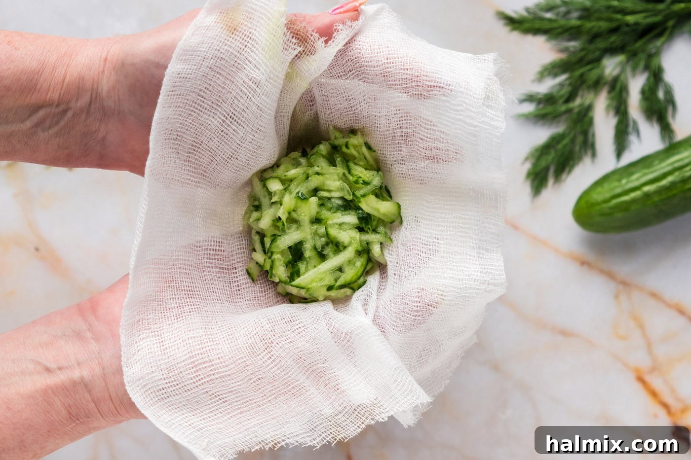 Shredded English cucumber being gathered in a cheesecloth, ready to be squeezed to remove excess liquid for Tzatziki Sauce, illustrating a crucial step for creamy texture.